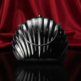 The Manay black shell-shaped handbag with silver chain on red satin background