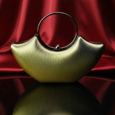 Modern gold evening handbag with round handle on red satin, luxury accessory from The Manay