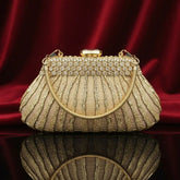 Elegant gold evening clutch purse with rhinestones and chain handle on red velvet by The Manay