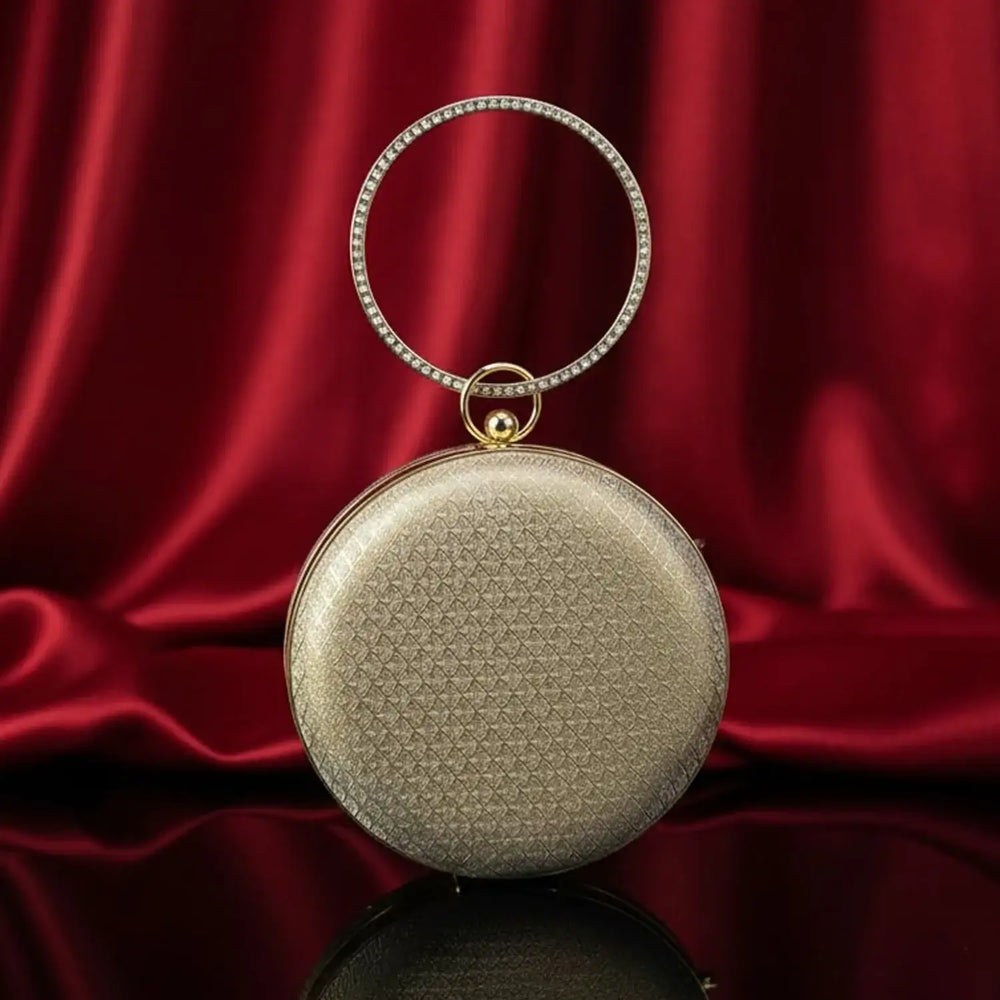 Elegant gold round handbag with jeweled handle on red silk background, The Manay luxury bag