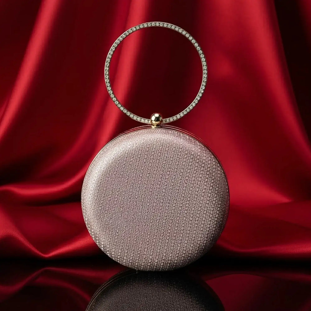 The Manay round glitter clutch bag with jeweled ring handle on red satin background