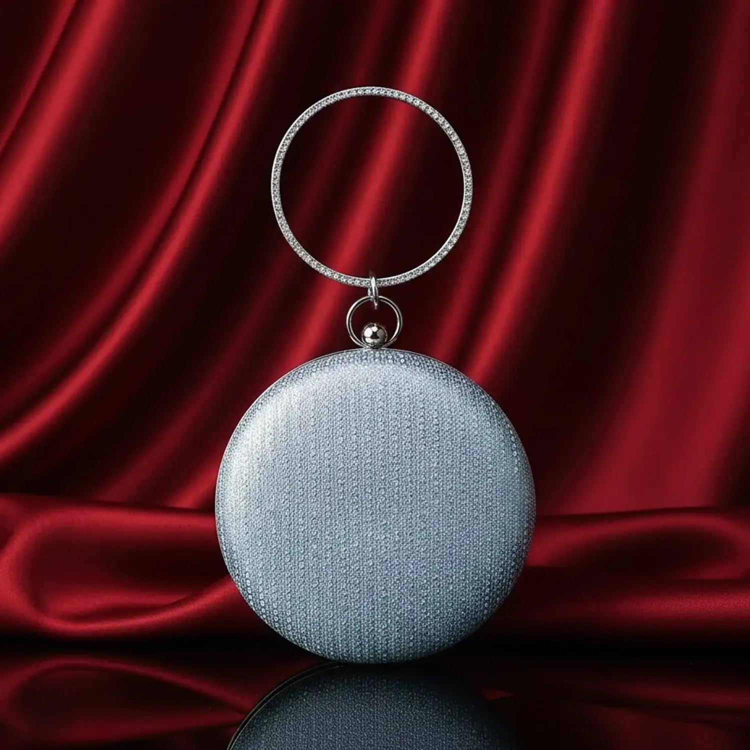 Silver round evening clutch bag on red satin background, luxury accessories by The Manay