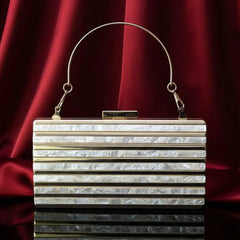 Elegant pearl white clutch bag with gold handle on red satin, The Manay accessory