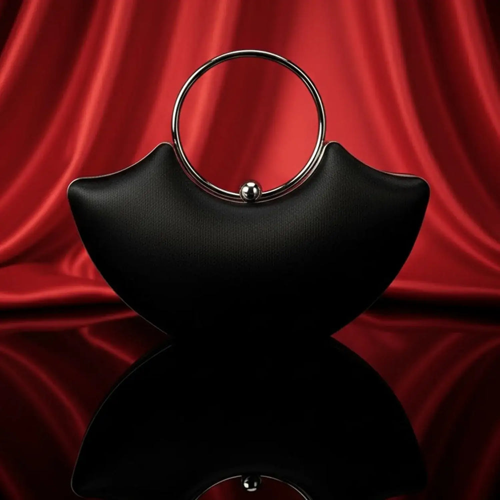 The Manay black designer handbag with silver ring handle on red satin background
