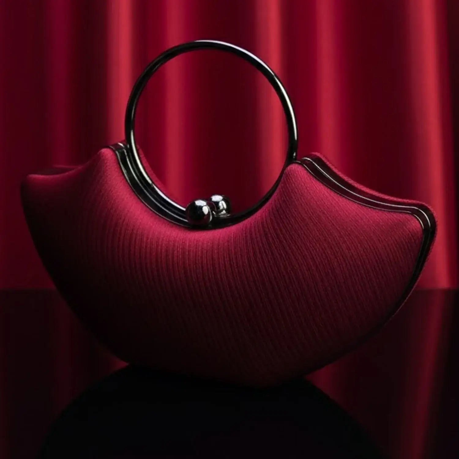 Red designer handbag with metal handle on glossy surface, luxury fashion by The Manay