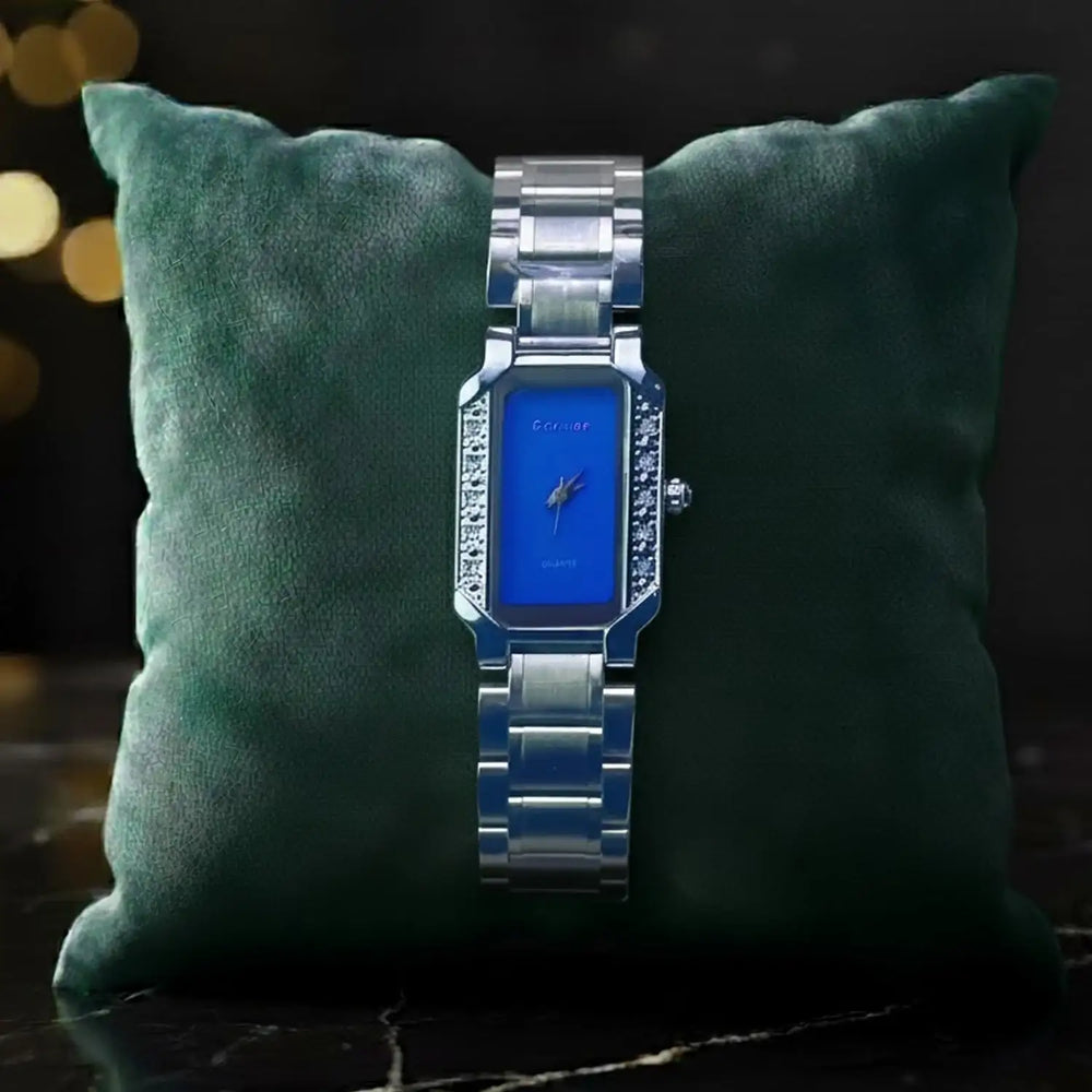 The Manay luxury silver wristwatch with blue face and diamond accents on green pillow display