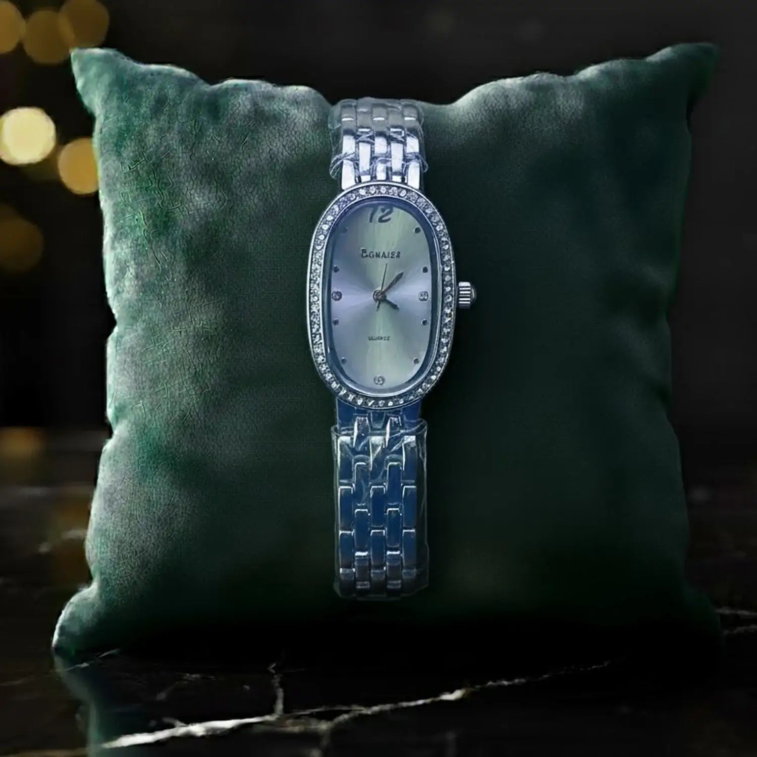 Elegant silver women's wristwatch with oval face on green cushion, Egnaïsa | ShopMidasLuxe
