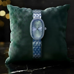 Elegant silver women's wristwatch with oval face on green cushion, Egnaïsa | ShopMidasLuxe