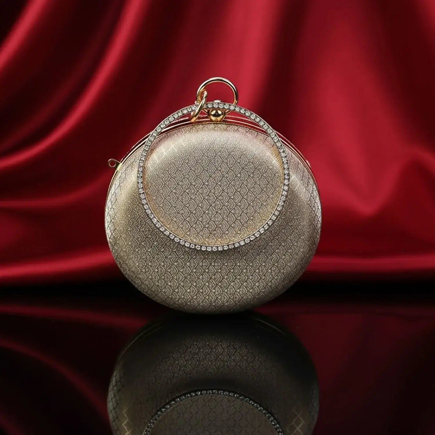 The Manay gold round evening clutch with diamond handle on red silk background