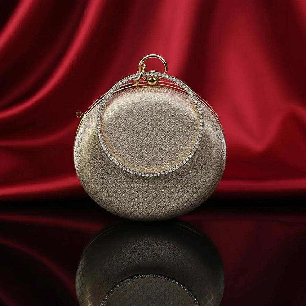 The Manay gold round evening clutch with diamond handle on red silk background