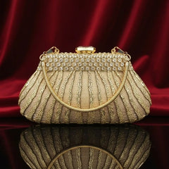 Elegant gold evening clutch purse with rhinestones and chain handle on red velvet by The Manay